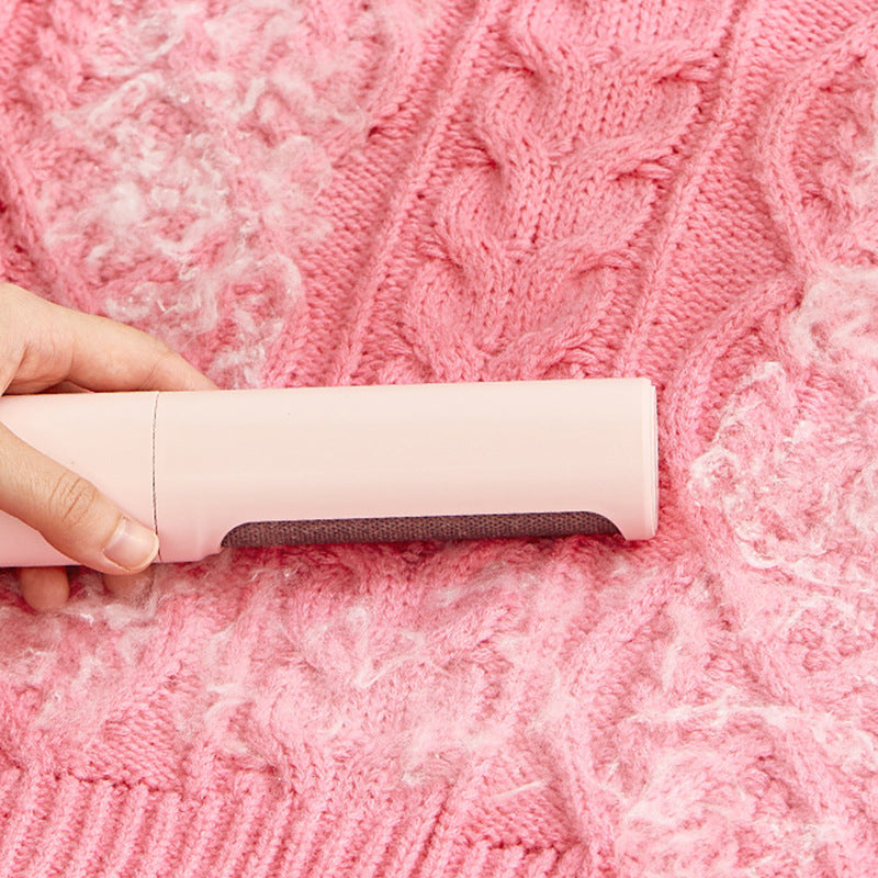 Pink reusable lint remover roller being used on a textured pink knitted fabric.